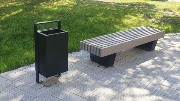 Outdoor metal trash can next to outdoor bench